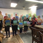 The proud local painters who took part in the finger painting flowers class show off their incredible works of art.